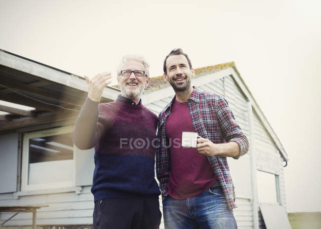 Отец и сын разговаривают и пьют кофе у дома — стоковое фото