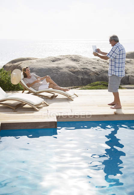 Älterer Mann fotografiert Freundin am Pool — Stockfoto
