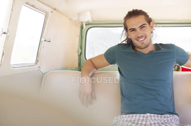 Чоловік посміхається на задньому сидінні фургона — стокове фото