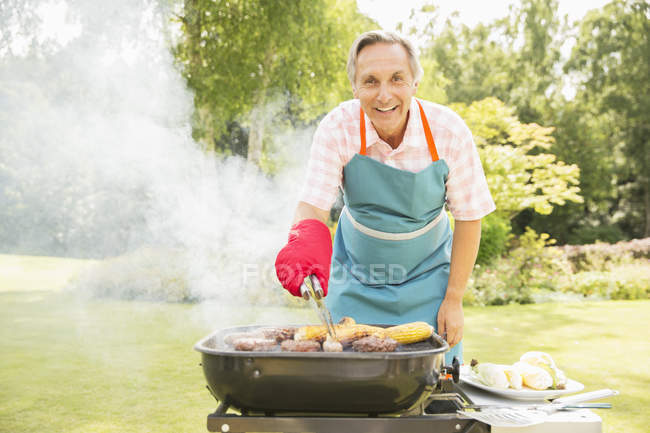 Человек жарит еду на гриле на заднем дворе — стоковое фото