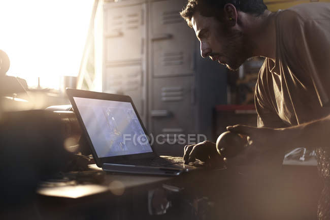 Blacksmith using laptop in forge — Stock Photo