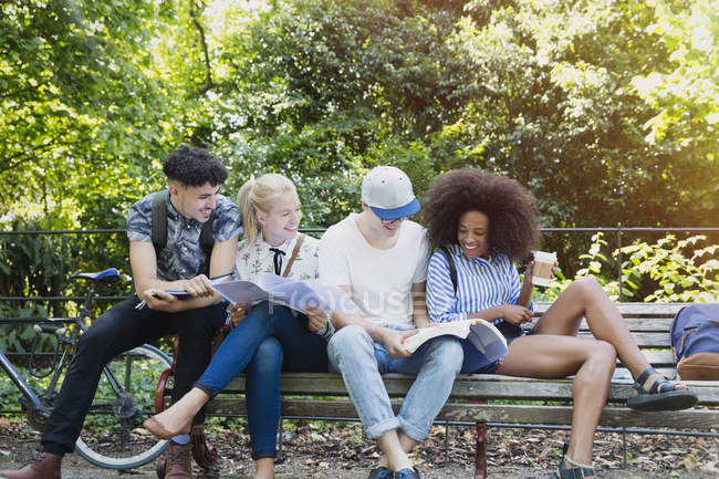 Студенты колледжа тусуются на скамейке в парке — стоковое фото