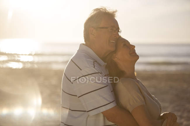 Літня пара обіймається на пляжі — стокове фото