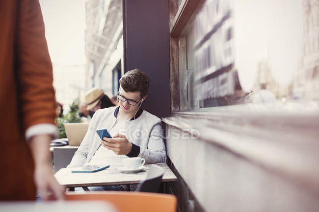 Homme écoutant des écouteurs avec lecteur mp3 au café trottoir — Photo de stock