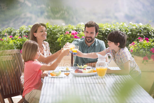 Dégustation familiale de verres de jus d'orange à table dans le jardin — Photo de stock