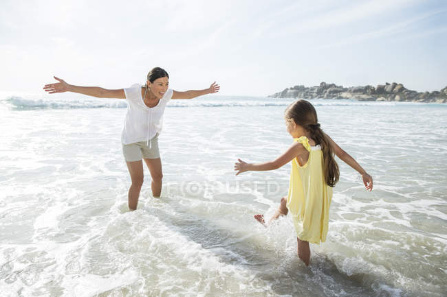 Мать и дочь играют в серфинге на пляже — стоковое фото