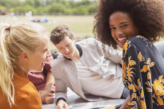 Portrait femme souriante traînant avec des amis dans un parc ensoleillé — Photo de stock