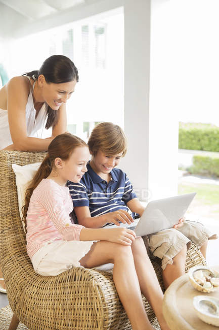 Mère et enfants utilisant un ordinateur portable dans le salon — Photo de stock