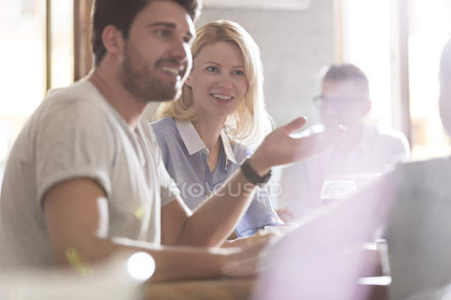 Sonrientes padres hablando y haciendo gestos a su hija en la cafetería - foto de stock