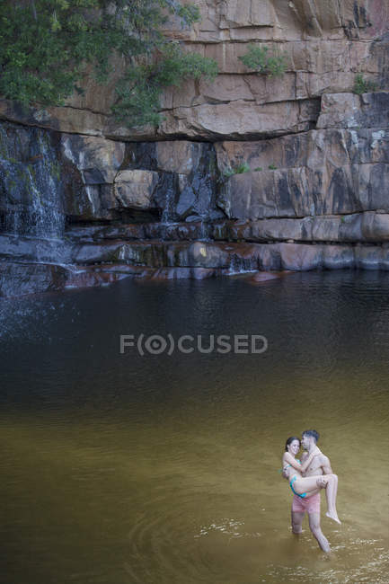 Mann trägt Freundin in Pool — Stockfoto