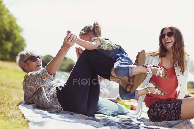 Playful grandmother and granddaughter on blanket in sunny field — Stock Photo