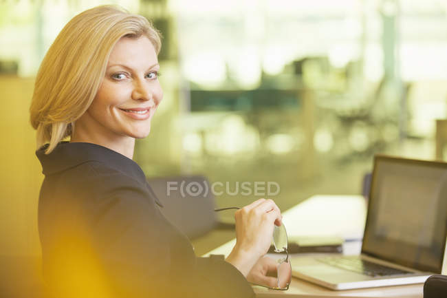 Empresária sorrindo para a mesa no escritório — Fotografia de Stock