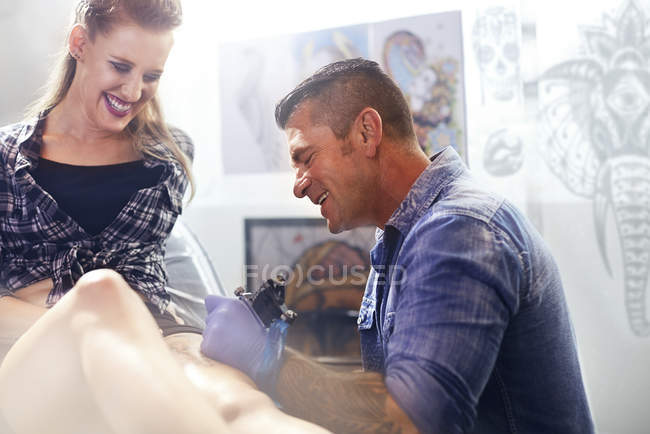 Tatuaggio artista tatuaggio donna coscia in studio — Foto stock