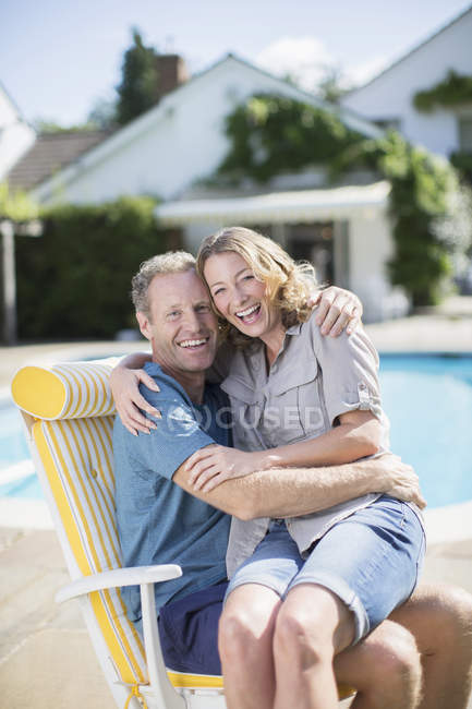 Couple sitting in lounge chair at poolside — Stock Photo