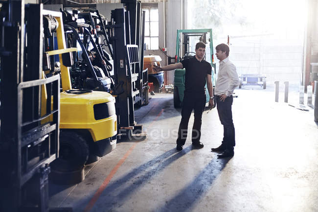 Meccanico e cliente parlando in officina di riparazione auto — Foto stock