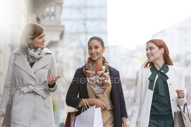 Mulheres com sacos de compras conversando e andando na cidade — Fotografia de Stock