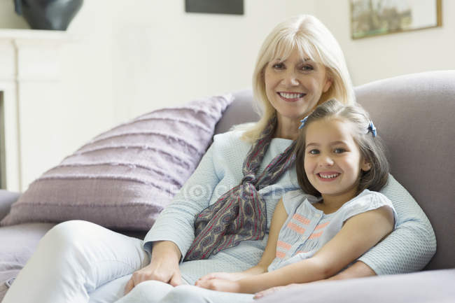 Portrait smiling grandmother and granddaughter on living room sofa — Stock Photo