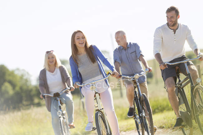 Счастливая семейная езда на велосипеде в солнечном поле — стоковое фото