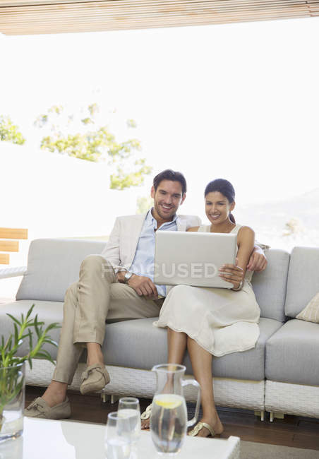 Casal usando laptop juntos no sofá — Fotografia de Stock