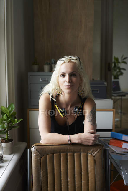 Portrait confident young woman with headphones and tattoo in home office — Stock Photo