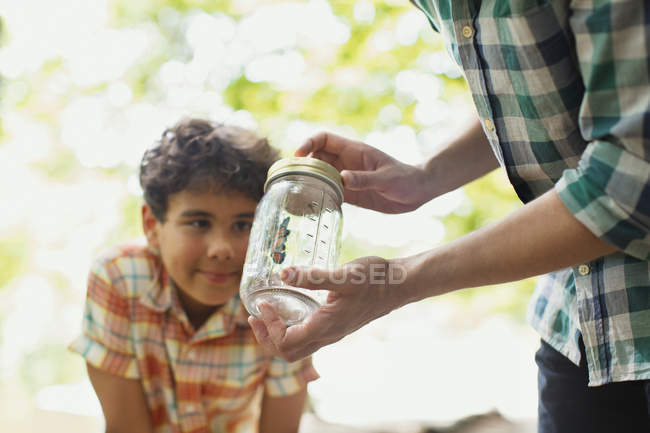 Отец и сын смотрят на бабочку в банке — стоковое фото