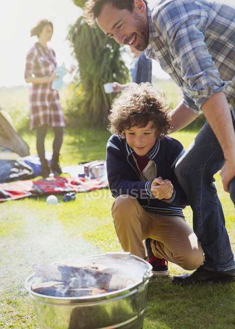 Father and son watching campfire ignite — Stock Photo