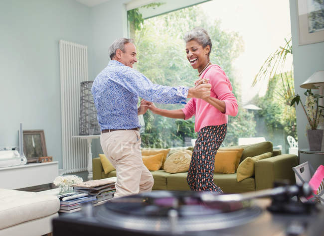 Playful mature couple dancing in living room — Stock Photo