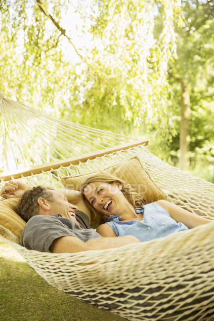 Feliz pareja relajándose en hamaca al aire libre - foto de stock