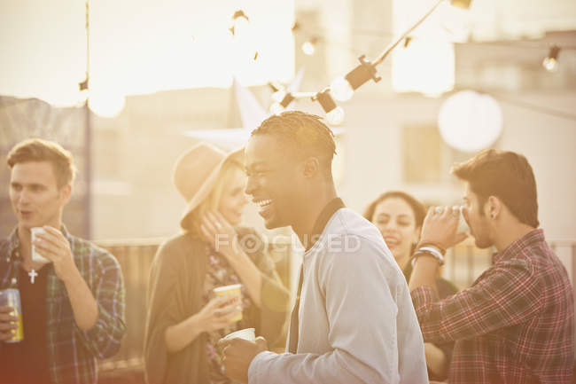 Jovem rindo e bebendo na festa no telhado — Fotografia de Stock