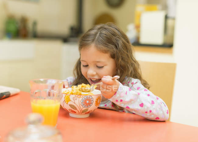 Chica comiendo cereales en la mesa del desayuno - foto de stock