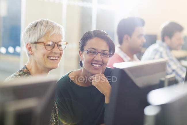 Усміхнені жінки за комп'ютером у навчальному класі для дорослих — стокове фото