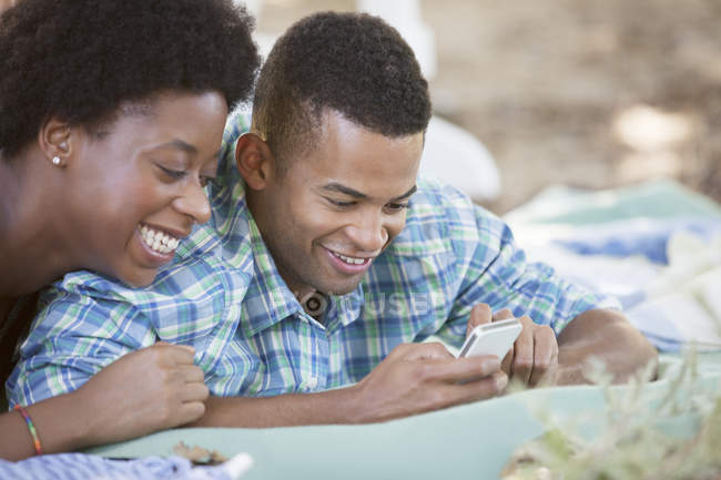Paar benutzt Handy auf Decke — Stockfoto