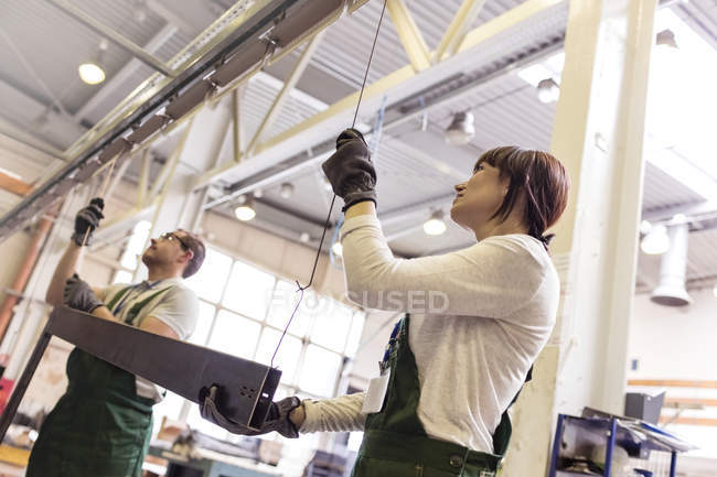 Робітники висять сталеву частину на заводі — стокове фото