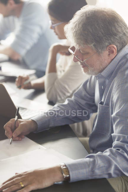 Hombre haciendo deberes en el aula de educación de adultos - foto de stock