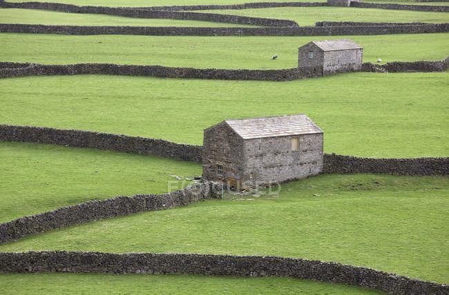 Edificios y muros de piedra en el paisaje rural - foto de stock