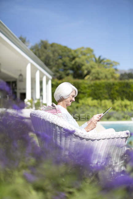Femme âgée utilisant une tablette numérique dans le jardin — Photo de stock