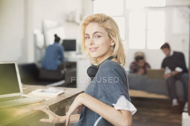 Retrato confiado joven estudiante universitaria con auriculares en el ordenador portátil - foto de stock
