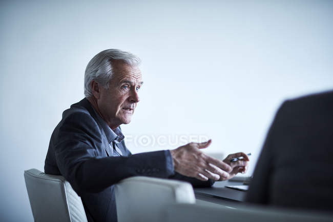 Hombre de negocios senior gesticulando y hablando en la reunión - foto de stock