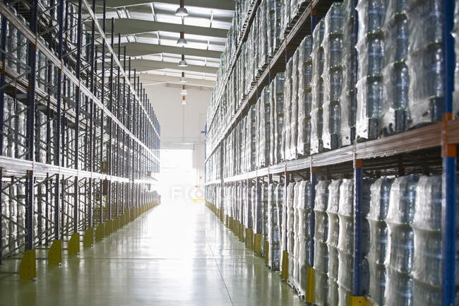 Pallets of water bottles on warehouse shelves — Stock Photo