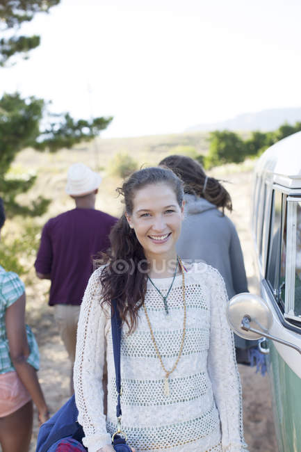 Mujer sonriendo por furgoneta en camino rural - foto de stock