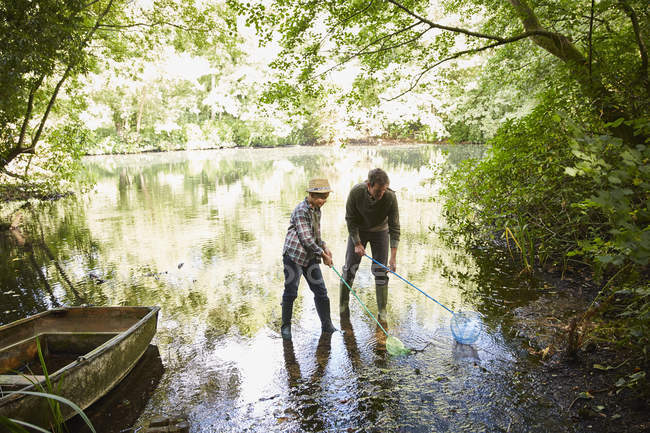 Father and son fishing with nets in forest pond — Stock Photo