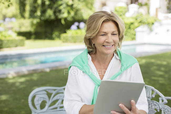 Старшая женщина использует цифровой планшет на заднем дворе — стоковое фото