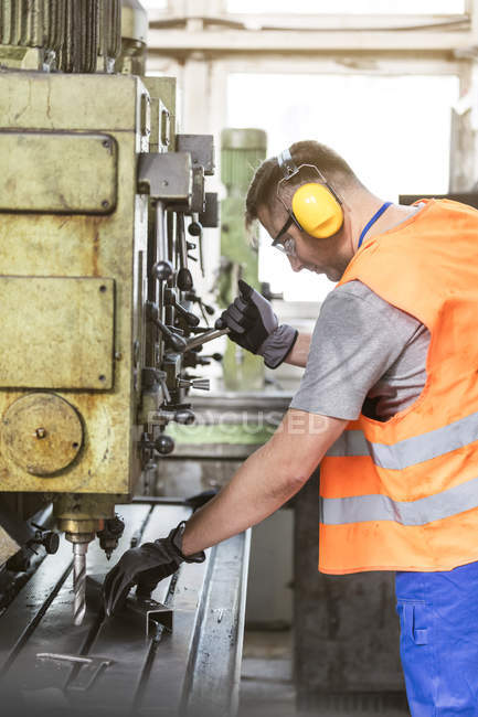 Trabalhador em vestuário de trabalho de protecção que utiliza máquinas na fábrica — Fotografia de Stock