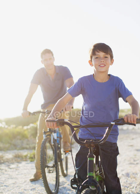 Vater und Sohn mit Fahrrädern am sonnigen Strand — Stockfoto