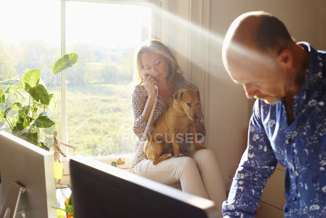 Pareja con perro en casa soleado oficina - foto de stock