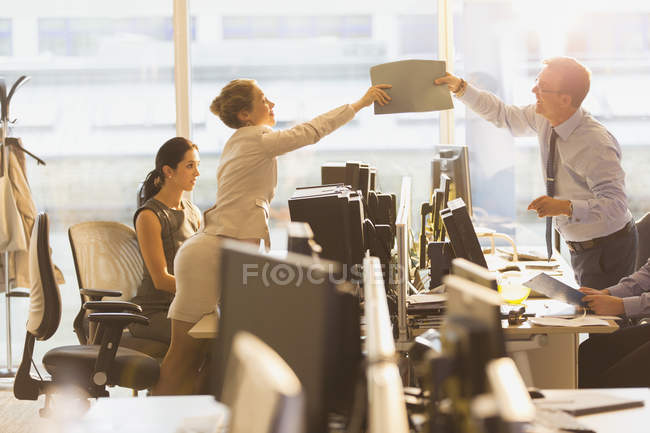 Empresário e empresária passando pasta sobre computadores no escritório — Fotografia de Stock