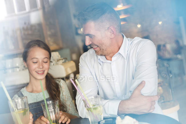 Отец и дочь пьют лимонад за столом кафе — стоковое фото