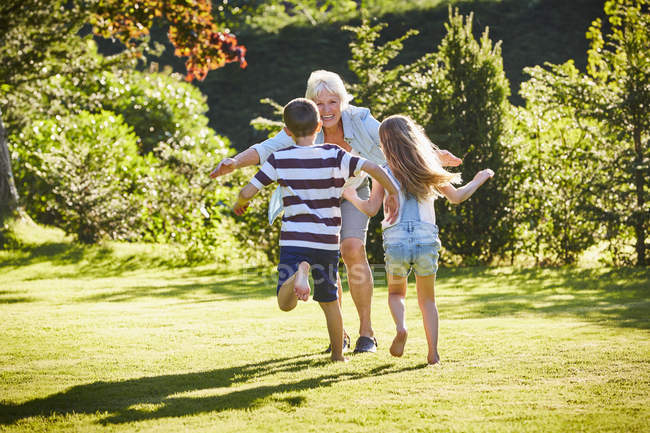 Внуки бегут к бабушке в солнечный сад — стоковое фото