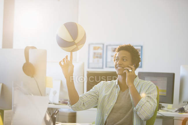 Бізнесмен обертається баскетболом на пальці в офісі — стокове фото