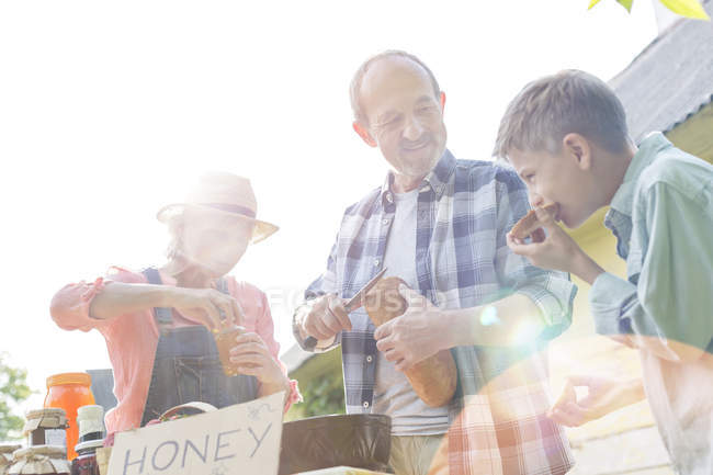 Grandparents and grandson tasting and selling honey at farmers market — Stock Photo